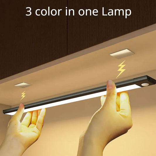 Light strip with '3 color in one Lamp' text held by hands against a wooden cabinet background.